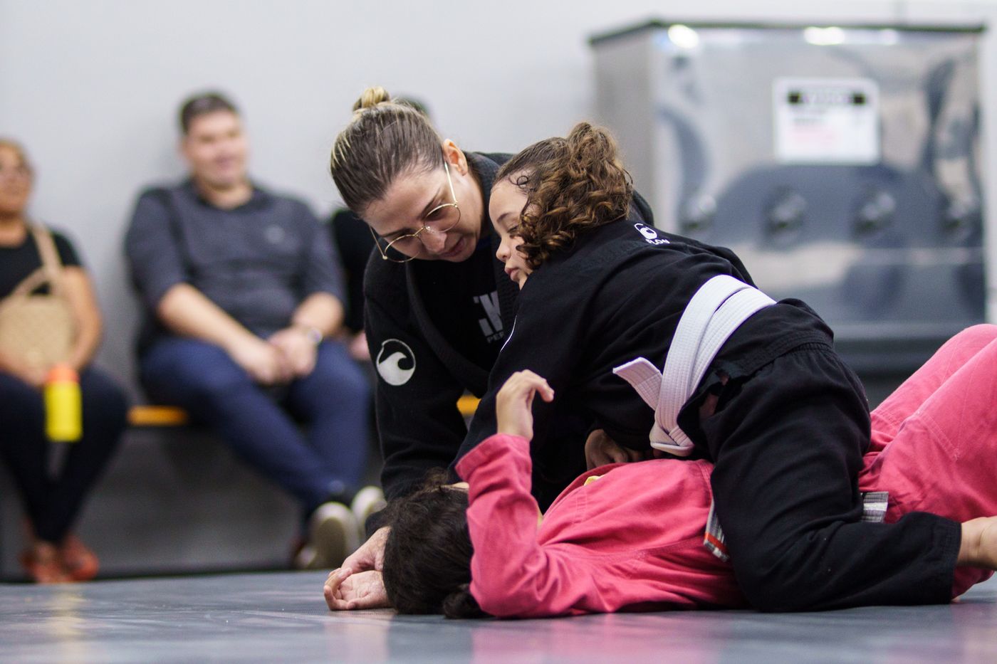 Professora corrigindo aluna durante o jiu-jitsu infantil da Flow